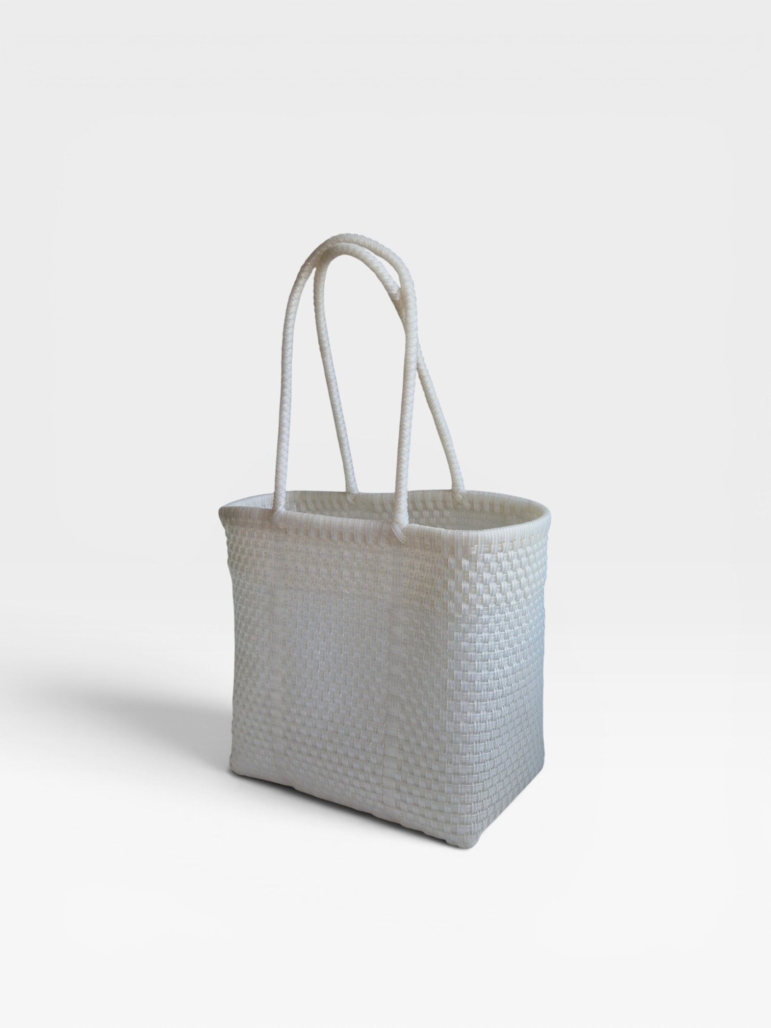 Alma Tote Chica in Clear — handgeflochtene Tragetasche aus recyceltem Kunststoff, kompakte Grösse mit langen Henkeln