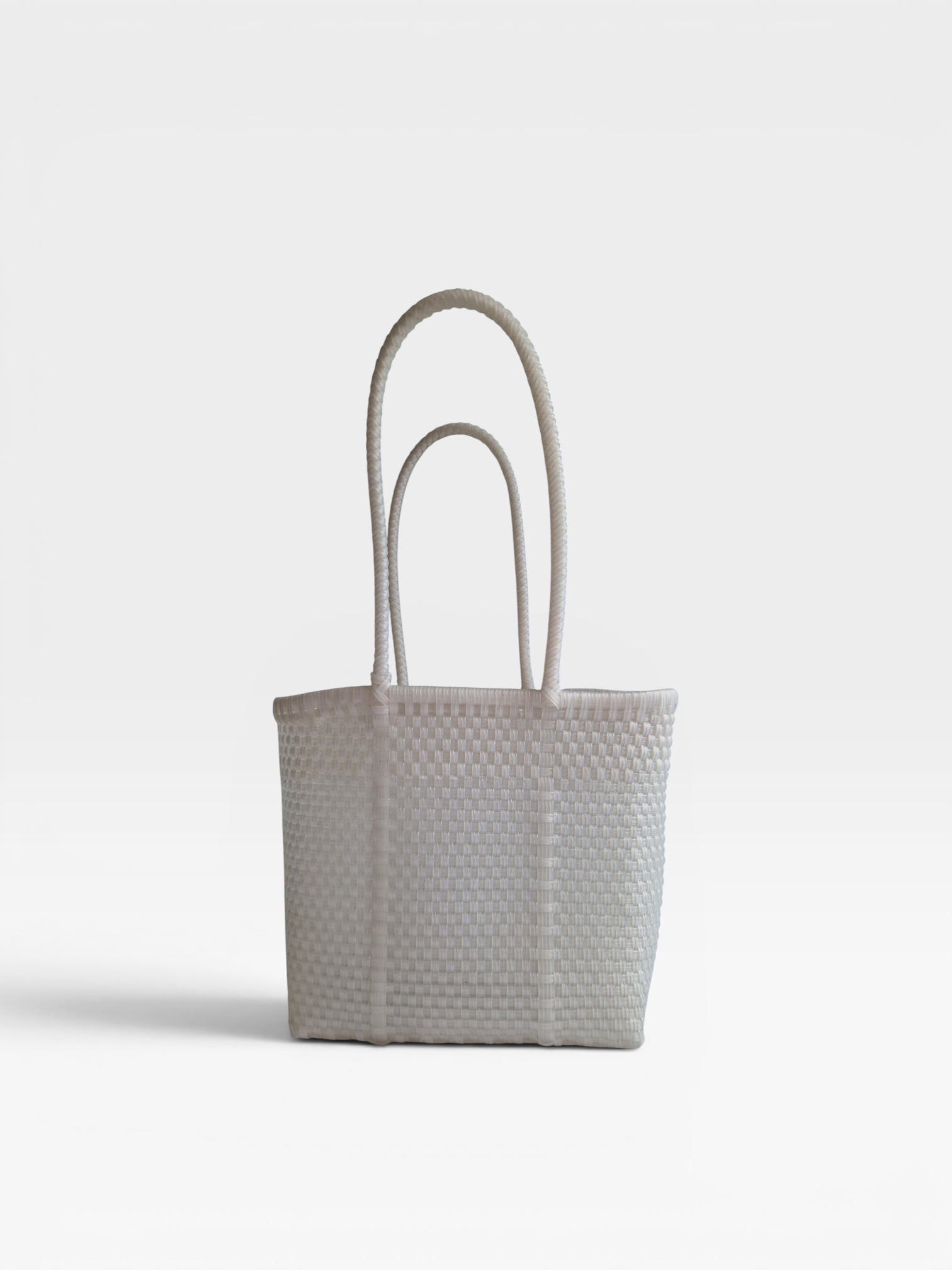 Alma Tote Chica in Clear — handgeflochtene Tragetasche aus recyceltem Kunststoff, kompakte Grösse mit langen Henkeln